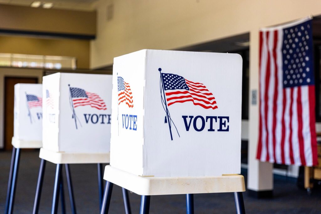 Color photo of an American voting center with small voting booths ready for voters to cast their ballots; Public domain image, courtesy of RawPixel.com
